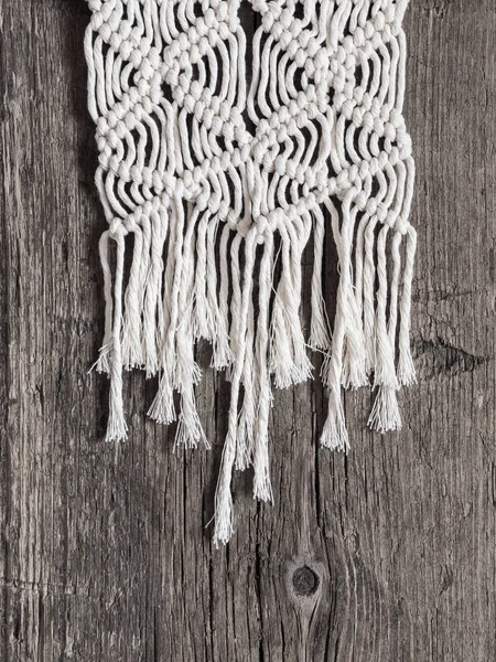 Macrame. Macrame weaving. White thread, wooden background, closeup