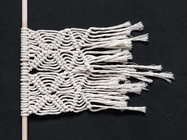 Macrame. Macrame weaving. White thread, black background, closeup