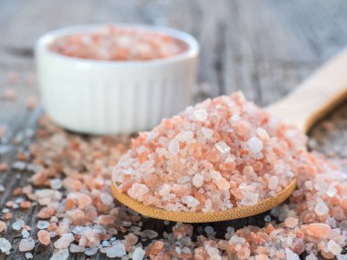 Himalaya tuz kaşık ahşap arka plan üzerinde pembe. Sağlıklı baharat tatlı