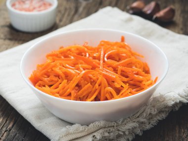 Fermente sebze, Kore havuç. Ahşap arka plan üzerinde beyaz tabak içinde Asya baharatlı salata