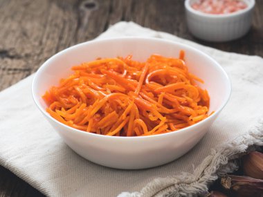 Fermente sebze, Kore havuç. Ahşap arka plan üzerinde beyaz tabak içinde Asya baharatlı salata