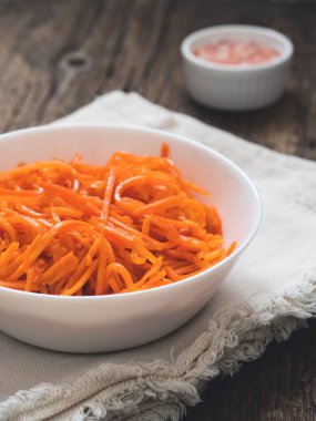 Fermente sebze, Kore havuç. Ahşap arka plan üzerinde beyaz tabak içinde Asya baharatlı salata