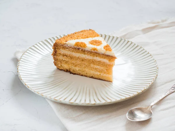 Piece of delicious cake. Delicate honey cake and sour cream. Dessert on a plate and white background