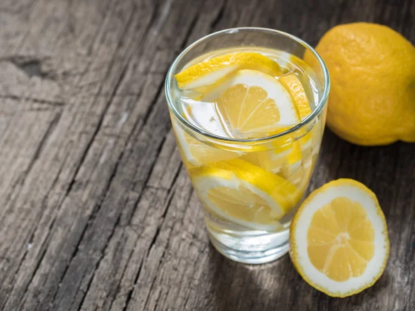Taze temiz su bir bardak limon dilimleri ile. Ahşap masa limonata. Su yaşam, sağlıklı içecek