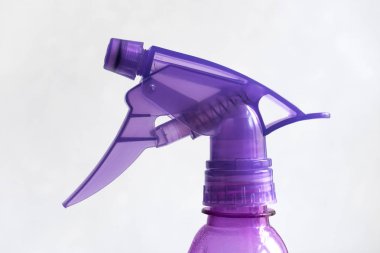 Sprey şişesi. Gri arka planda küçük plastik mor bahçe püskürtücü