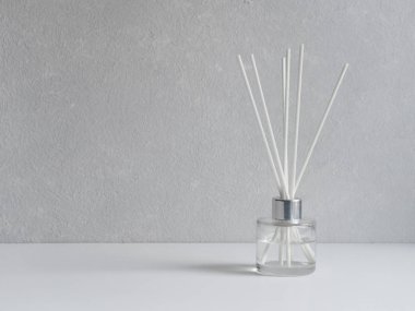 Aromatizer. Gri arka plan üzerinde beyaz sazlıklar ile şeffaf bir cam şişede Aromatik hava spreyi