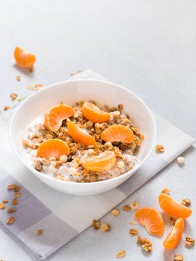 Sağlıklı kahvaltı. Beyaz arka planda tropikal meyveler, taze mandalina ve yoğurt ile pişmiş müsli