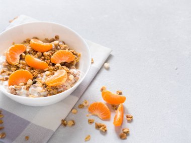 Sağlıklı kahvaltı. Beyaz arka planda tropikal meyveler, taze mandalina ve yoğurt ile pişmiş müsli