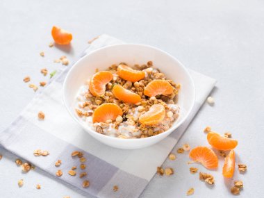 Sağlıklı kahvaltı. Beyaz arka planda tropikal meyveler, taze mandalina ve yoğurt ile pişmiş müsli