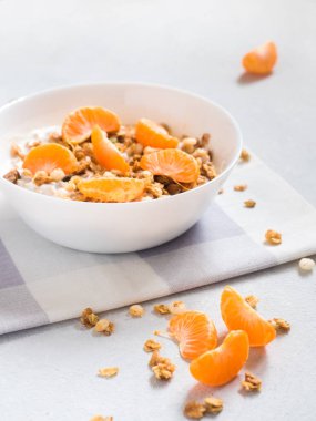 Sağlıklı kahvaltı. Beyaz arka planda tropikal meyveler, taze mandalina ve yoğurt ile pişmiş müsli