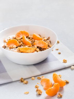 Sağlıklı kahvaltı. Beyaz arka planda tropikal meyveler, taze mandalina ve yoğurt ile pişmiş müsli