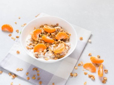 Sağlıklı kahvaltı. Beyaz arka planda tropikal meyveler, taze mandalina ve yoğurt ile pişmiş müsli