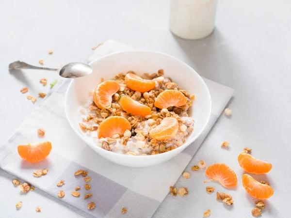 Sağlıklı kahvaltı. Beyaz arka planda tropikal meyveler, taze mandalina ve yoğurt ile pişmiş müsli