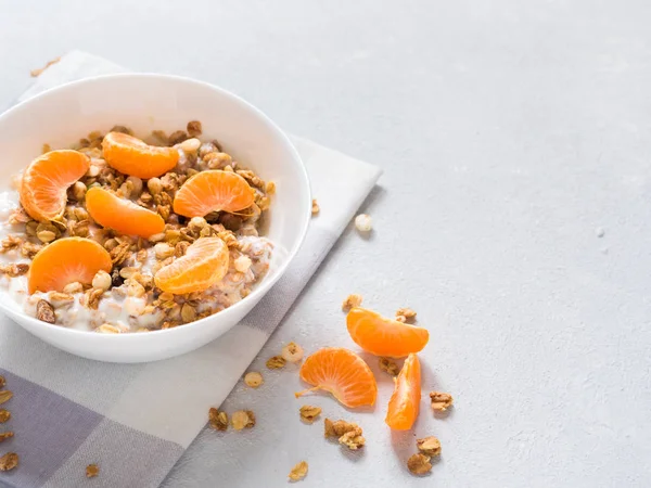 Sağlıklı kahvaltı. Beyaz arka planda tropikal meyveler, taze mandalina ve yoğurt ile pişmiş müsli