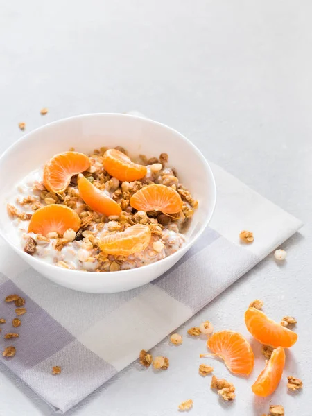 Sağlıklı kahvaltı. Beyaz arka planda tropikal meyveler, taze mandalina ve yoğurt ile pişmiş müsli