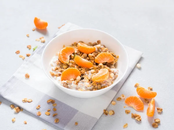 Sağlıklı kahvaltı. Beyaz arka planda tropikal meyveler, taze mandalina ve yoğurt ile pişmiş müsli