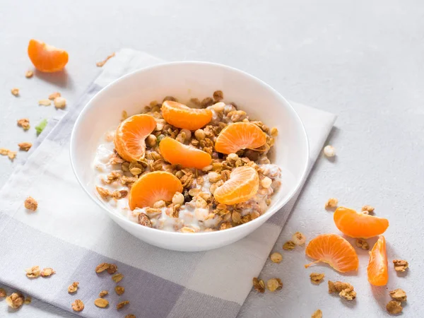 Sağlıklı kahvaltı. Beyaz arka planda tropikal meyveler, taze mandalina ve yoğurt ile pişmiş müsli