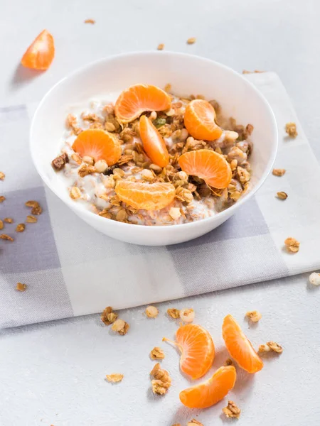 Sağlıklı kahvaltı. Beyaz arka planda tropikal meyveler, taze mandalina ve yoğurt ile pişmiş müsli
