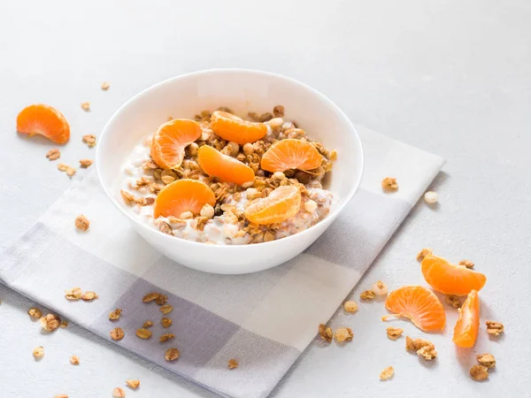 Sağlıklı kahvaltı. Beyaz arka planda tropikal meyveler, taze mandalina ve yoğurt ile pişmiş müsli