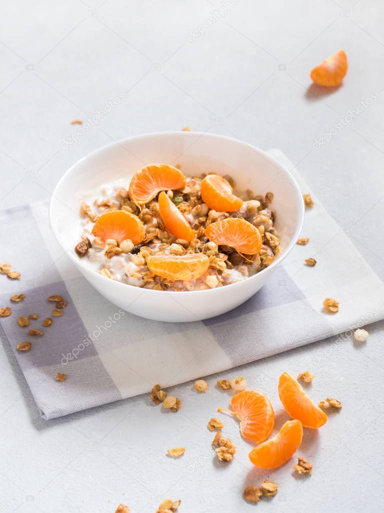 Healthy breakfast. Baked muesli with tropical fruits, fresh tangerines and yogurt on white background