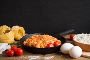 Ahşap bir masa üzerinde siyah bir tavada domates sosu ve fesleğen ile iştah açıcı geleneksel klasik İtalyan makarna. Tex için alan