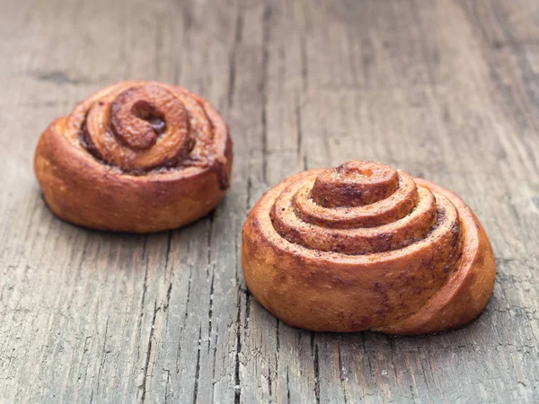 Confectionery baking. Sweet fresh soft roll bun with cinnamon on wooden background. Cinnabon closeup