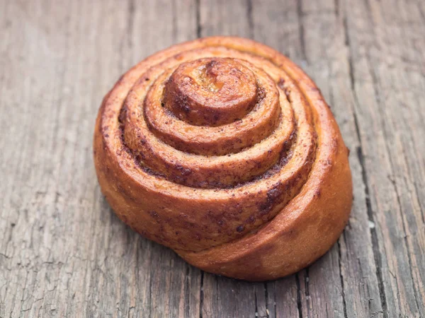 Confectionery baking. Sweet fresh soft roll bun with cinnamon on wooden background. Cinnabon closeup — Stock Photo, Image