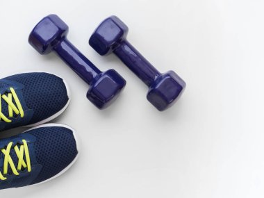 Spor ve aktif yaşam tarzı kavramı. Mor koşu ayakkabıları ve beyaz arka planda iki halter. Düz yatıyordu. Üstte görüntü