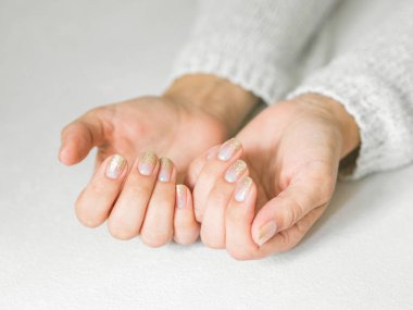 Manikür salon konsepti. Beyaz bir arka plan üzerinde altın tırnak manikür ile güzel kadın elleri. Altın oje. Closeup