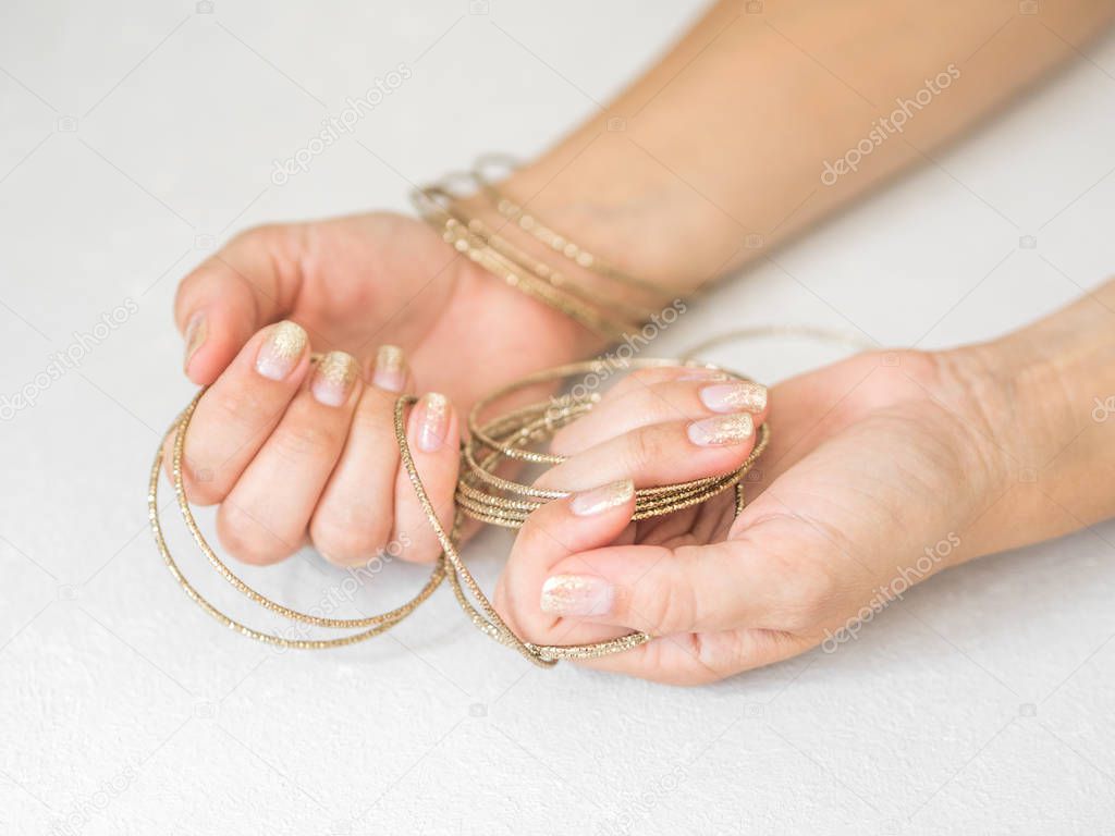 Manicure salon concept. Beautiful women hands with golden nail manicure on a white background. Gold nail polish. Closeup