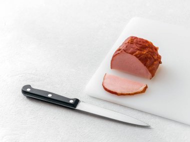 Kesme tahtası ve beyaz masada mutfak bıçağı üzerinde karbonat et dilim kesin. Minimalizm. Gıda konsepti