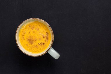 Süt ve tarçınlı zerdeçal latte. Sağlık ve yaşam iksiri. Geleneksel sağlıklı Hint detoks içeceği. Siyah arkaplan, üst görünüm, kopyalama alanı