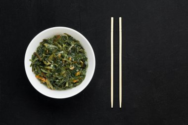 Beyaz tabakta mayalanmış yosunlu yosun salatası. Geleneksel Japon yemekleri, Asya mutfağı. Siyah arkaplan, üst görünüm, kopyalama alanı