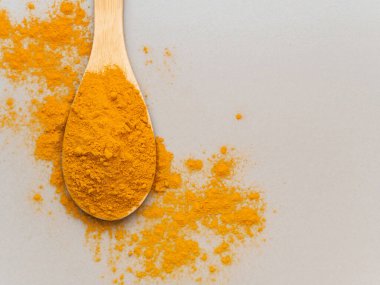 Zerdeçal tozu. Geleneksel Hint altın sarısı sağlıklı baharatı gri arka planda tahta kaşıkta. Üst görünüm