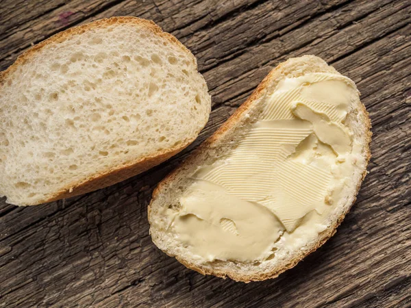 Tahtaya tereyağı sürülmüş beyaz ekmek dilimi. Üst Manzara. Yakın plan.