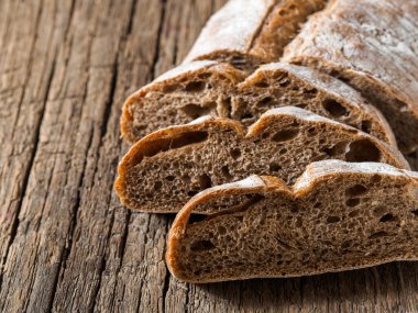 Ciabatta. Tahta zemin üzerinde zeytin yağından yapılmış füme kabuklu koyu sağlıklı, açık dokulu İtalyan ekmeği. Yakın plan..