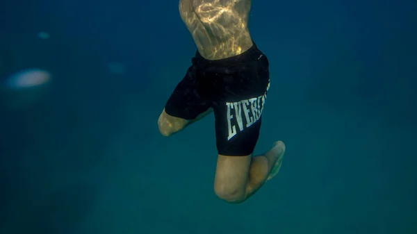 Panorâmica cena homem debaixo de água e fundo azul — Fotografia de Stock