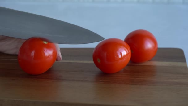 Snijden Van Rode Tomaten Helften Met Keukenmes Houten Snijplank — Stockvideo