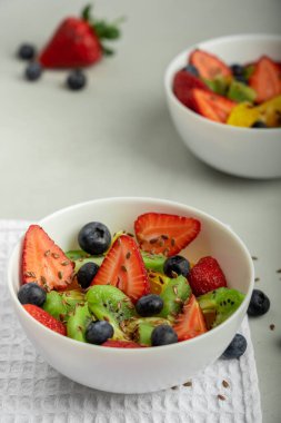 Karışık meyve ve böğürtlen salatası beyaz kase üzerinde mutfak masasında beyaz peçete