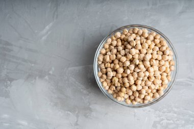 Sağdaki beton yüzeyde duran çiğ nohut dolu cam kase. Kopyalama alanı olan resim, yatay yönelim. Nohut et analoğu olarak vegan diyeti için yararlıdır.