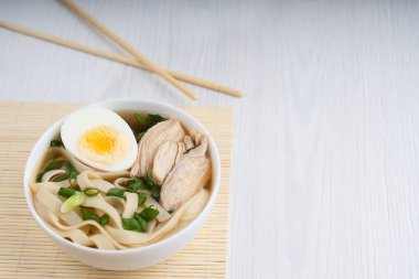 Baharatlı Asya ramen çorbası. Tavuk suyundan yapılmış. Erişte, yarım yumurta, et dilimleri ve yeşil soğan ile süslenmiş. Kopyalama alanı olan resim