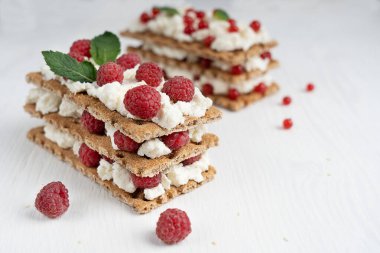 Üç katmanlı diyet sandviçin yakın görüntüsü taze ekmek, maskaron ve ahududu ile süslenmiş beyaz ahşap yüzey üzerine susam. Seçici odaklı resim