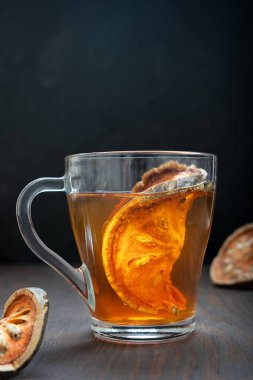 Tayland geleneksel matoom çayı, kuru bael meyvesinden yapılmış, ahşap elma olarak da bilinir, mutfakta koyu ahşap arka planda cam bir fincanda. Seçici odaklı resim, dikey yönelim