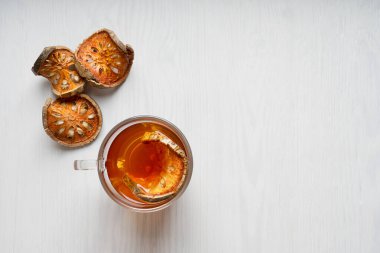 Thai şifalı matoom çayının üst görüntüsü kuru bael meyve dilimlerinden yapılmıştır, taş elma olarak da bilinir, beyaz ahşap arka planda cam bardak içinde. Kopyalama alanı ve yatay yönelimli resim