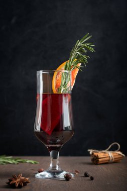 Soğuk kış tatillerinde hazırlanmış sıcak kırmızı baharatlı şarap. Portakal dilimleri ve taze biberiyeyle süslenmiş. Etrafı anason yıldızı ve tarçınla kaplı.