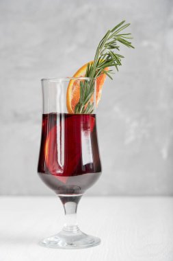 Baharatlı sıcak kırmızı şarap kadehi genellikle kış tatillerinde portakal dilimleri ve beyaz ahşap masada taze biberiye ile süslenir. Dikey yönelim