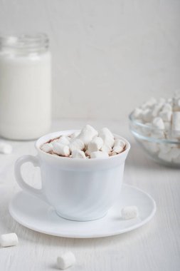 Soğuk sonbahar ve kış mevsimlerinde hazırlanmış ev yapımı kakao içecekleriyle dolu beyaz bardakta marşmelov ve mutfaktaki ahşap zemin üzerinde bir kavanoz süt servis edilir. Dikey yönelim