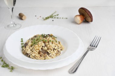 Kremalı risotto ya da İtalyan arborio pirinç tabağı çorba, mantar, kekik, zeytin yağı ve parmesan peyniri tabakta beyaz ahşap zemin üzerinde beyaz şarap ile servis edilir. Kopyalama alanı olan resim