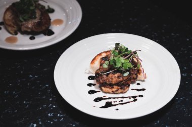 Siyah bir masada iki tabak kaz ciğeri.