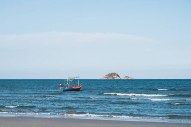 Güneşli bir günde sahilde küçük bir balıkçı teknesi yüzüyor.